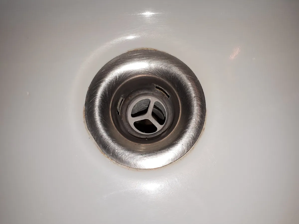 Chrome drain cover in a white bathroom sink