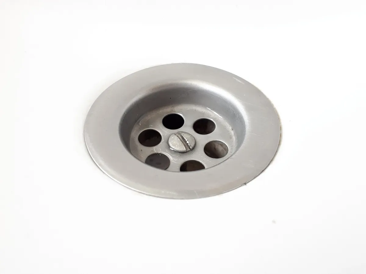 White porcelain basin drain with round holes, viewed from above